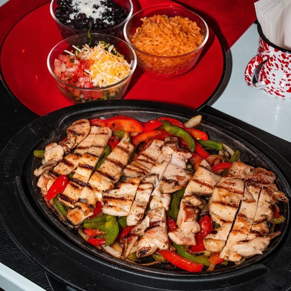 Calle Taco chicken fajitas with grilled peppers and onions, served with rice, beans, and pico de gallo.
